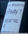 Close-up of an Islington Council sticker on a lamppost showing contact number for reporting faults.